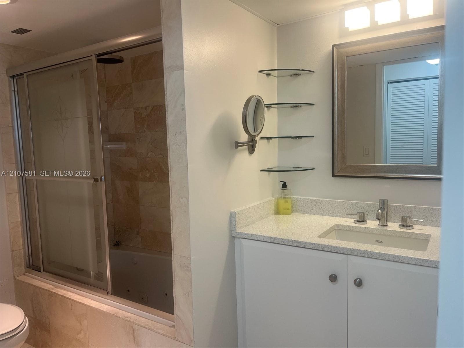 Vanity with light-colored countertop and integrated sink, framed mirror, and chrome fixtures
