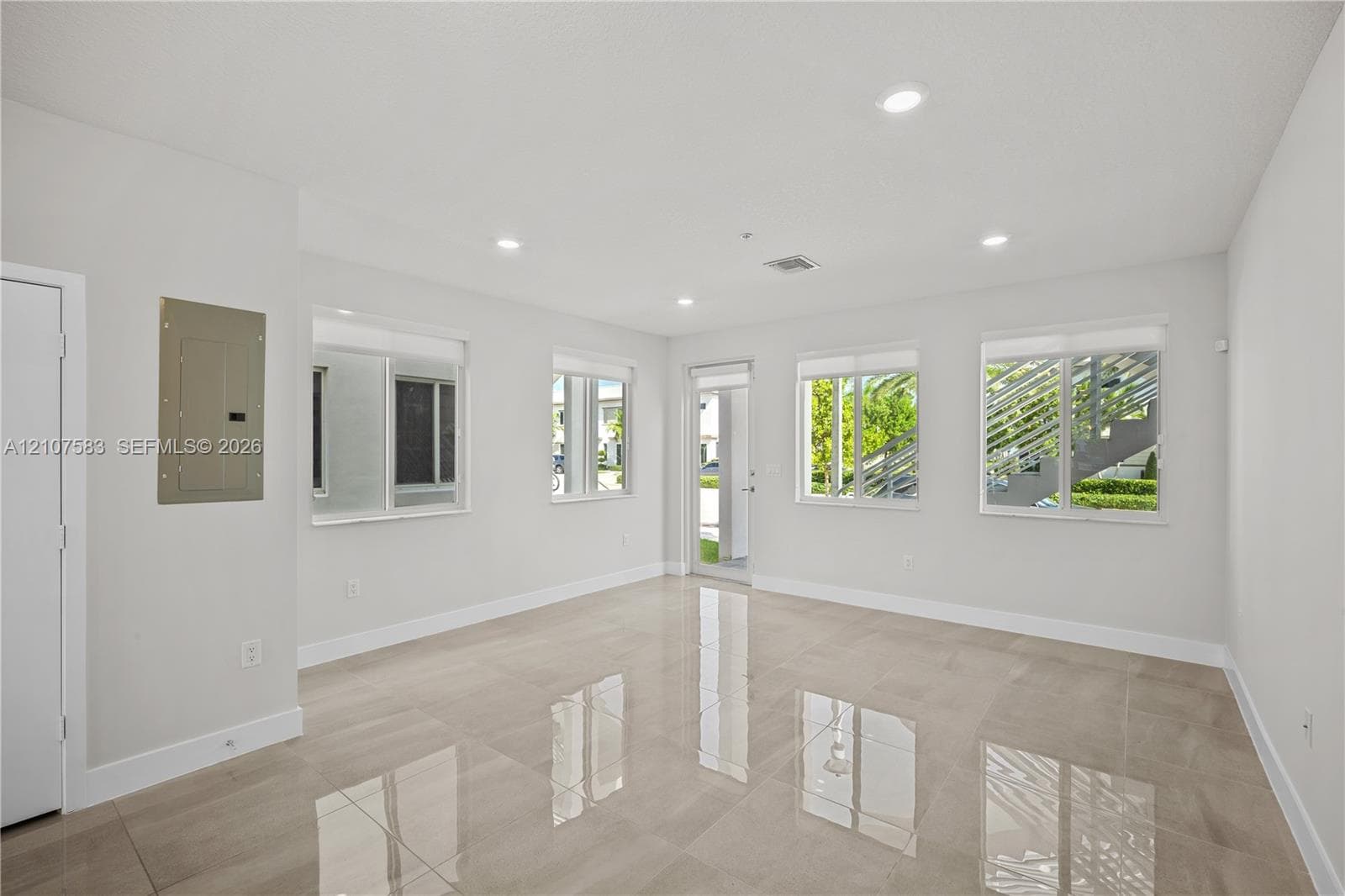 Neutral-toned interior featuring large-format tile flooring, recessed ceiling lighting, and multiple windows providing natural light