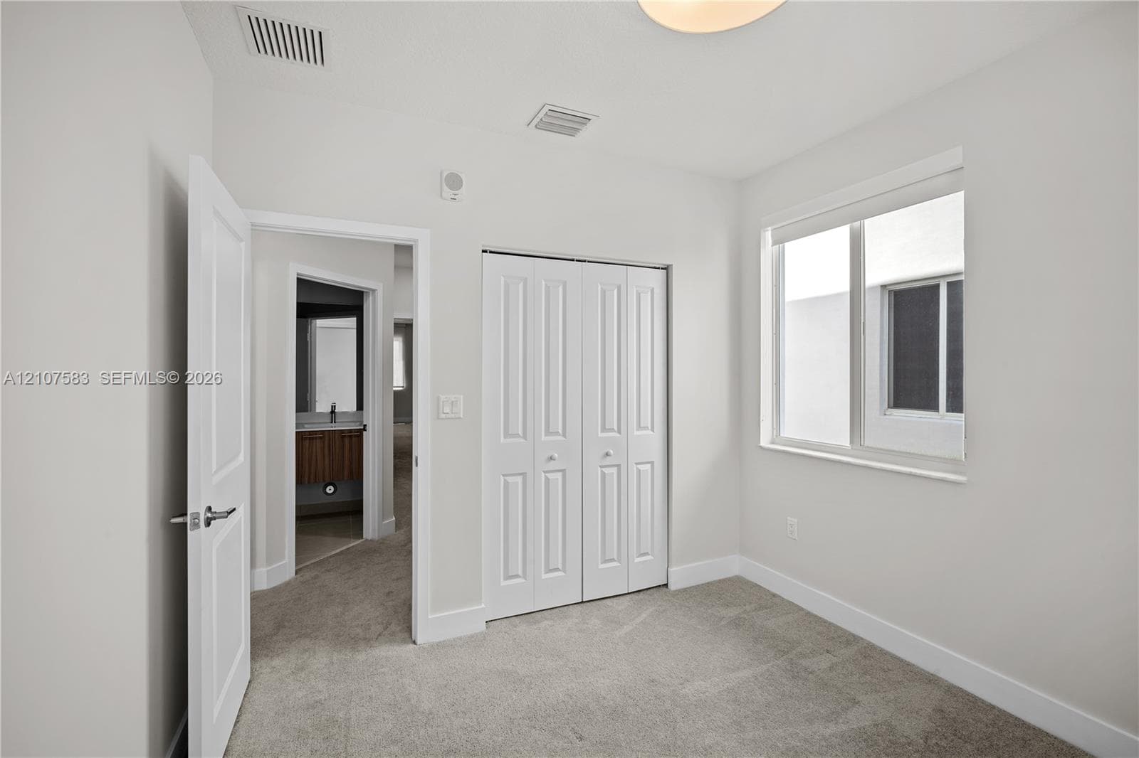 Neutral-toned carpeted flooring, bi-fold closet doors, and a double-pane window