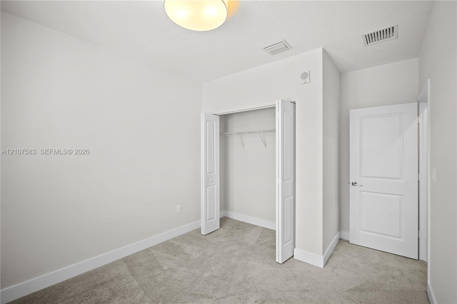 Neutral interior featuring neutral wall paint, carpeted flooring, a closet with bi-fold doors, and a paneled interior door