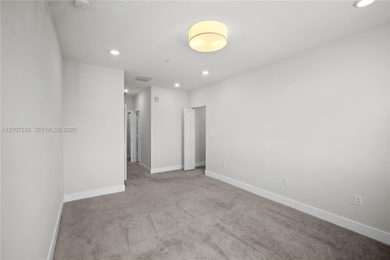 Interior space featuring neutral wall tones, plush carpeting, a central drum-style ceiling light, and recessed lighting