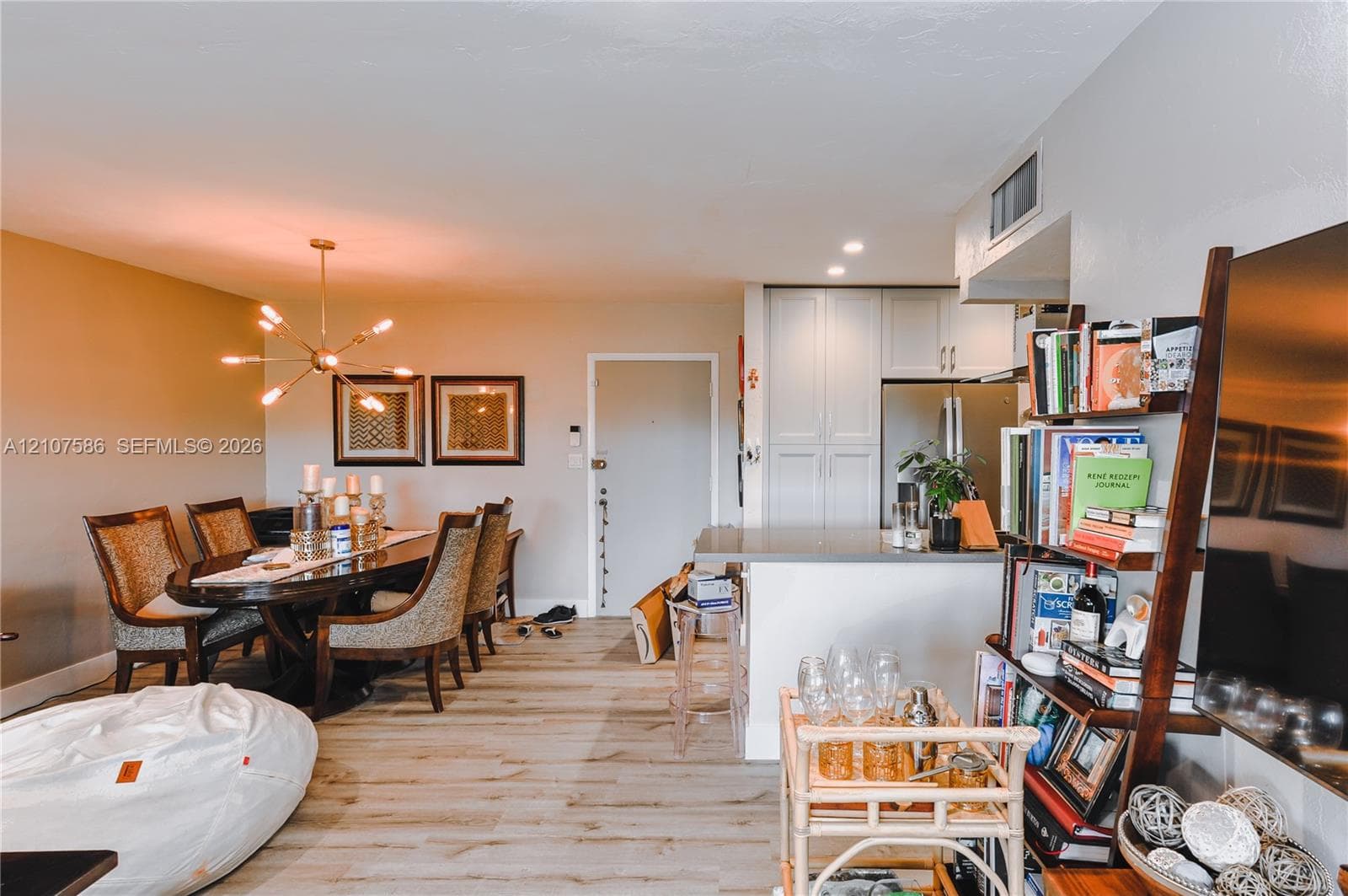 Open-concept area featuring wood-finish flooring, a multi-arm sputnik-style chandelier, and a breakfast bar with stone-finish countertops