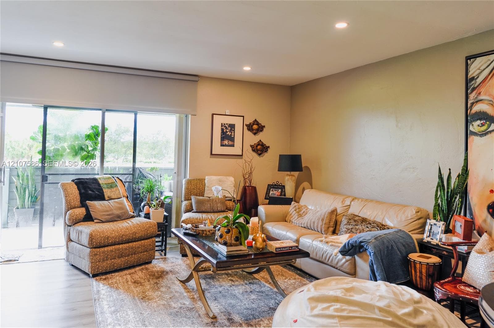Neutral wall finishes, recessed lighting, and large sliding glass door with a retractable roller shade, featuring wood-finish flooring