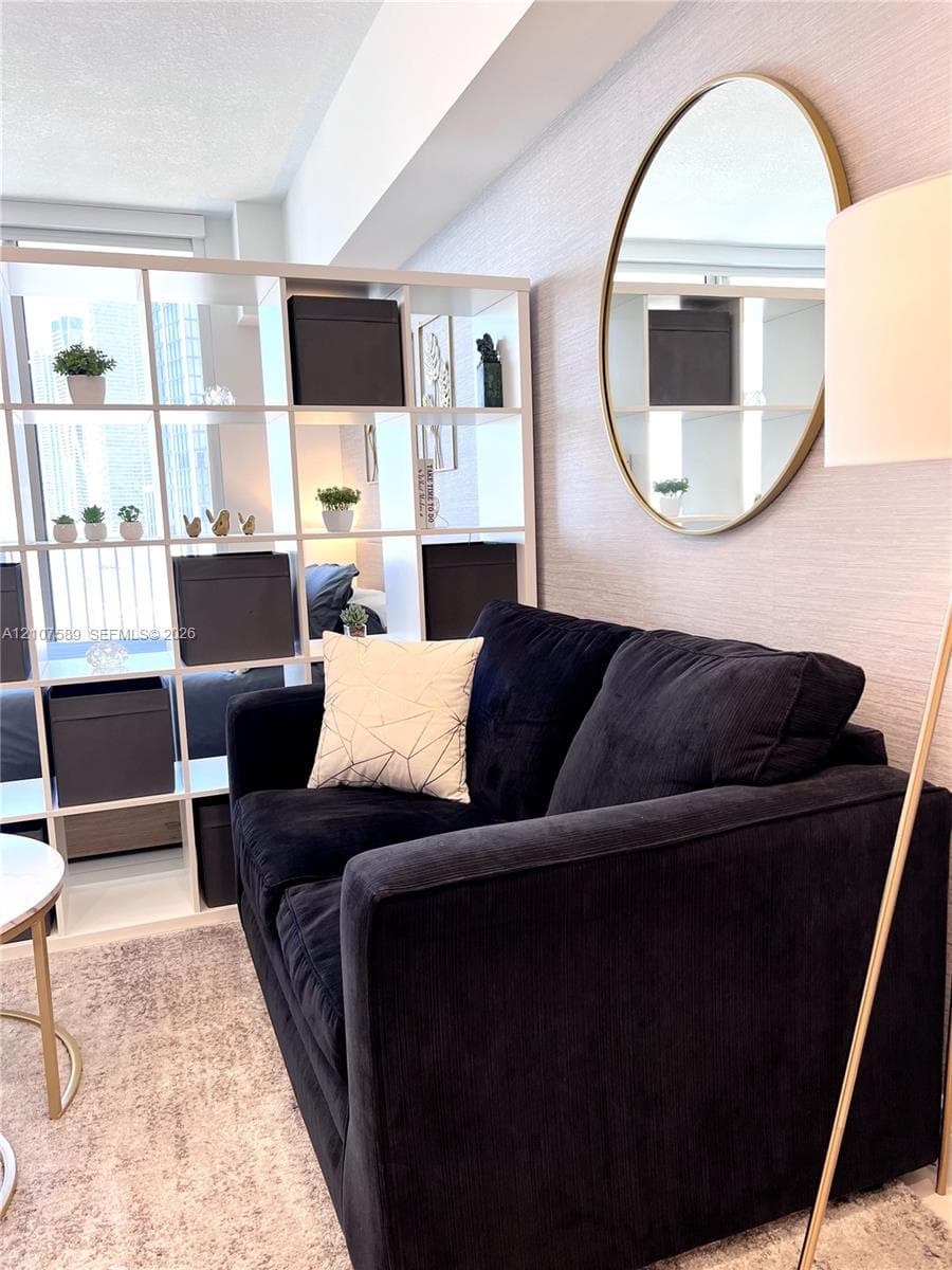 Textured wall treatment and neutral color palette featuring an oval wall-mounted mirror