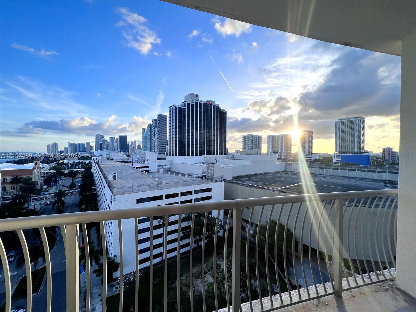 Private balcony featuring a vertical metal railing with a skyline cityscape