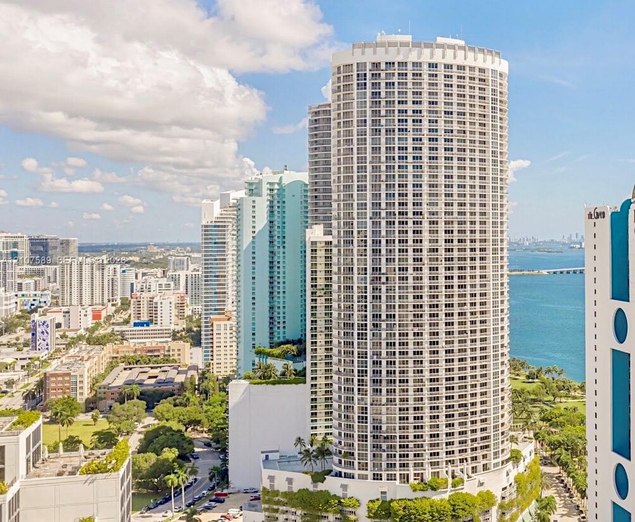 High-rise residential tower featuring a cylindrical glass-and-concrete facade, private balconies, and an urban waterfront location