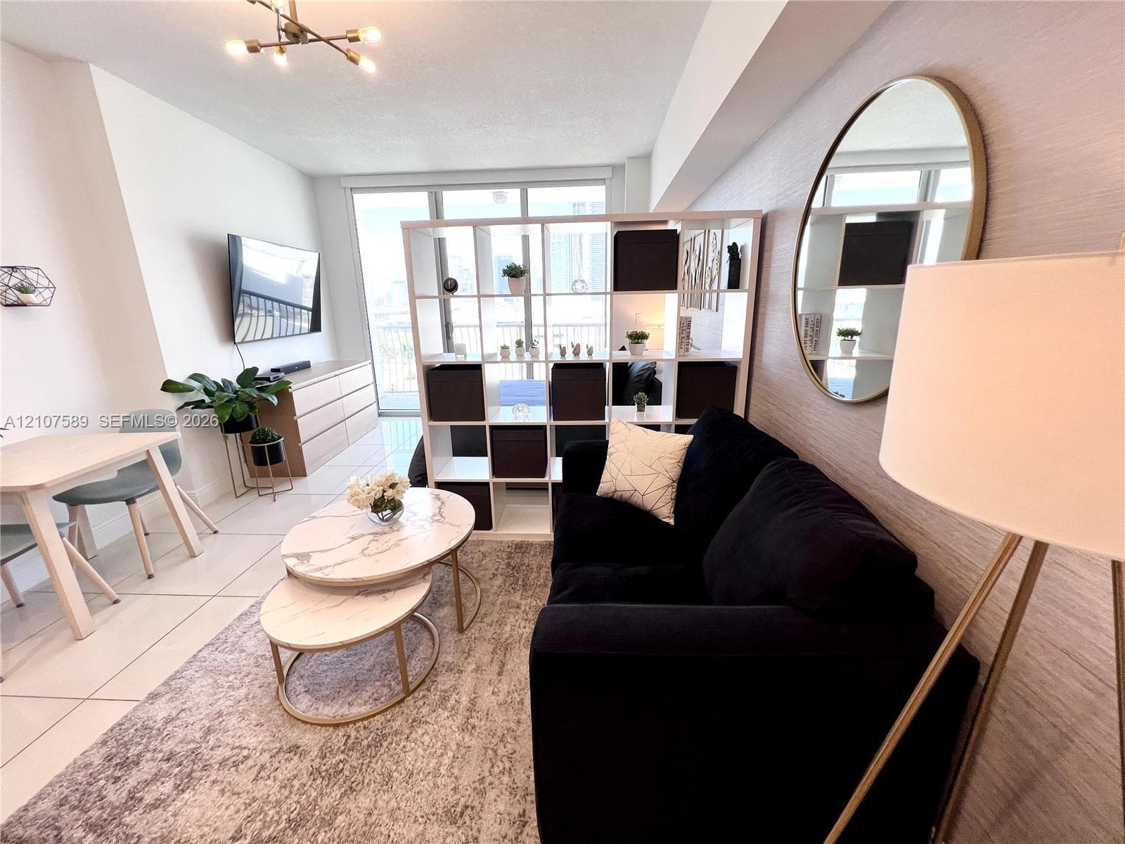 Open-concept living space featuring large-format tile flooring, textured wallpaper, and floor-to-ceiling glass patio doors