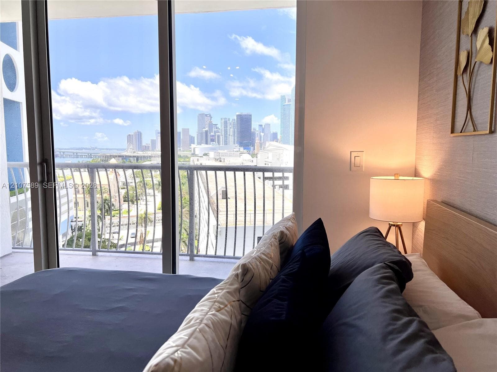 Floor-to-ceiling sliding glass door, private balcony with metal railing, and textured wall finish