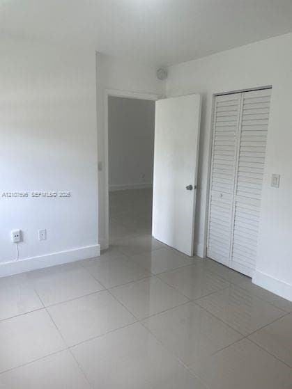 Neutral-toned large format tile flooring, white interior walls, and bi-fold closet doors