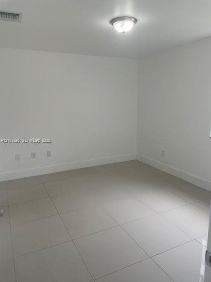 Neutral-toned interior space featuring polished large-format tile flooring, smooth wall finishes, and a dome-style flush-mount ceiling light fixture