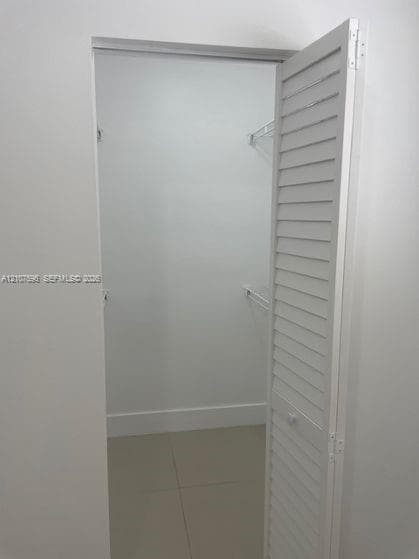 Storage space featuring white louvered doors and interior wire shelving