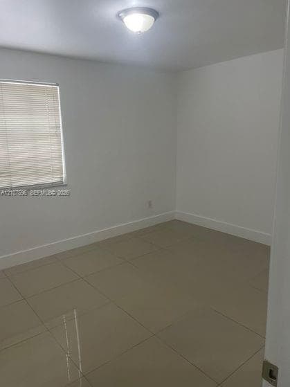 Neutral interior room featuring large-format tile flooring, crisp white walls, and a recessed ceiling light fixture