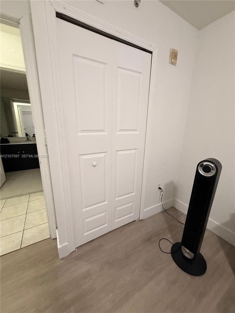 Bi-fold closet doors featuring a raised-panel design and neutral wood-finish flooring