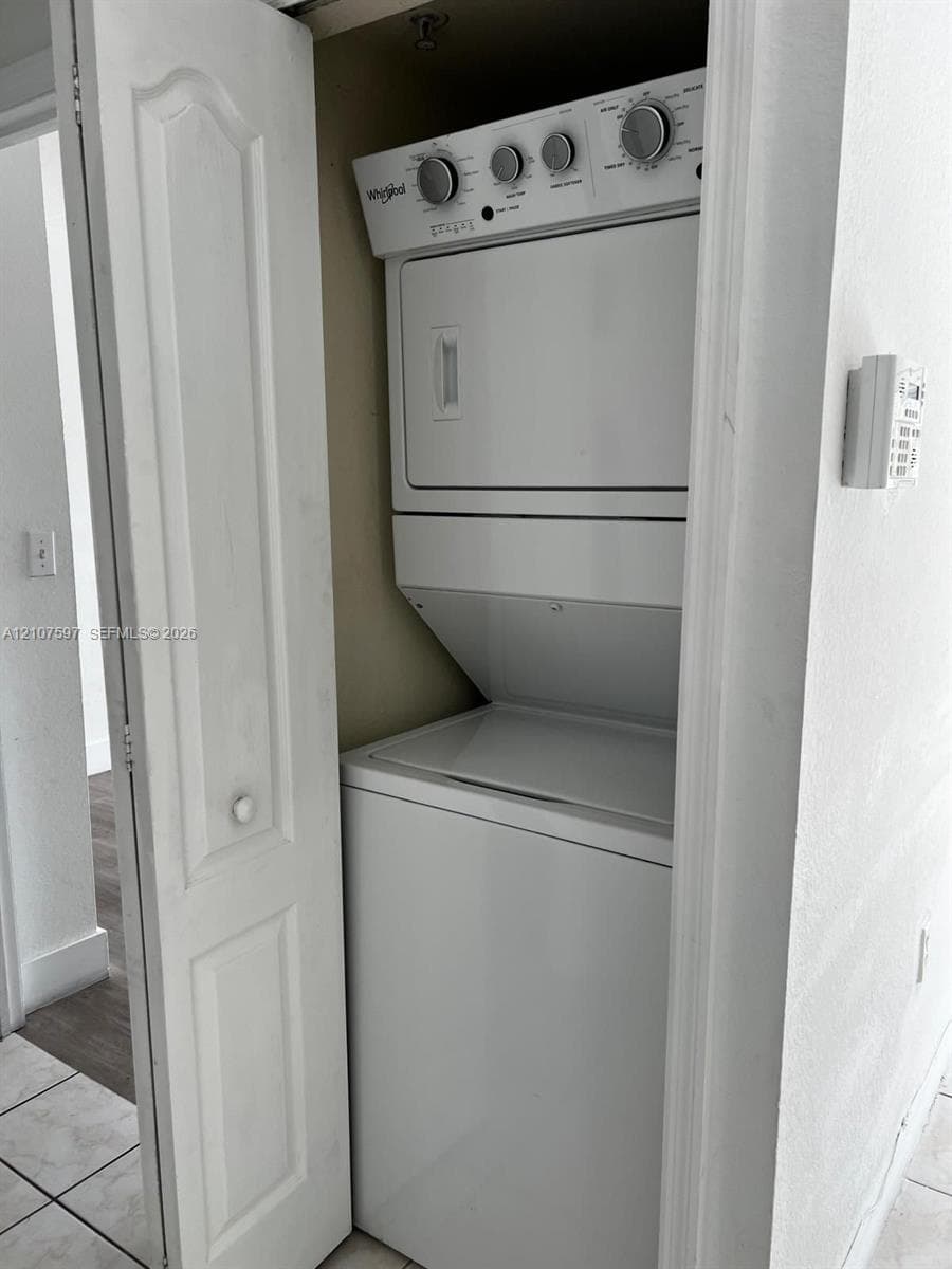 Enclosed laundry closet featuring a stacked white washer and dryer unit