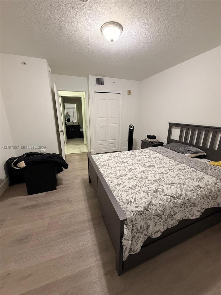 Room featuring wood-finish flooring, a double-door closet, and flush-mount overhead lighting