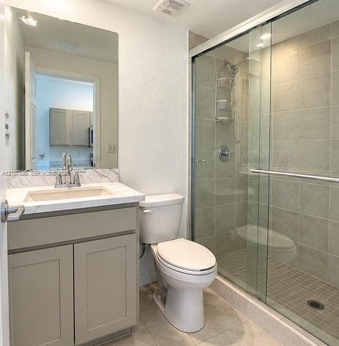 Bathroom featuring a vanity with stone-patterned countertop, under-mount sink, chrome faucet, and a walk-in shower with a sliding glass door and tiled walls