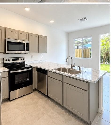 Kitchen featuring light-toned cabinetry, stone-patterned countertops, stainless steel appliances, a stainless steel dual-basin sink with a gooseneck faucet, and tile flooring