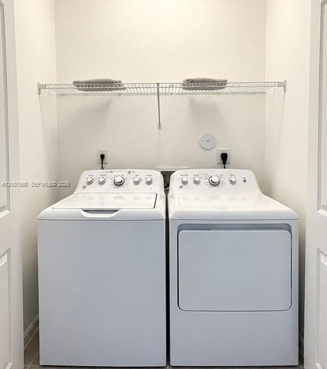 Dedicated laundry alcove featuring side-by-side white top-load washer and dryer with a wire-grid upper shelving unit