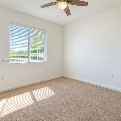 Neutral-toned wall-to-wall carpeting, window with horizontal blinds, and a multi-blade ceiling fan with a central light fixture