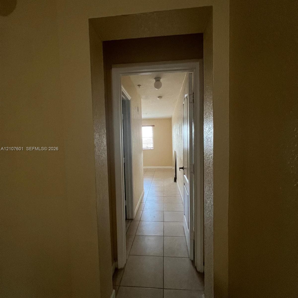 Ceramic tile flooring, white-trimmed door frames, and flush-mount ceiling light fixture