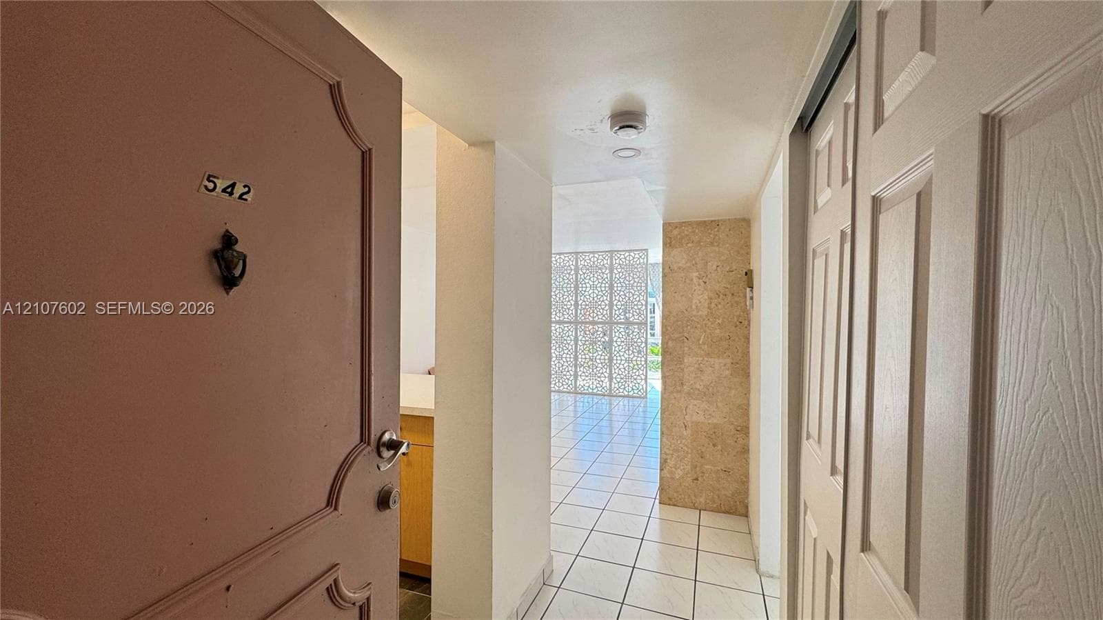 Entryway featuring a decorative metal screen, stone-tiled accent wall, recessed lighting, and tile flooring