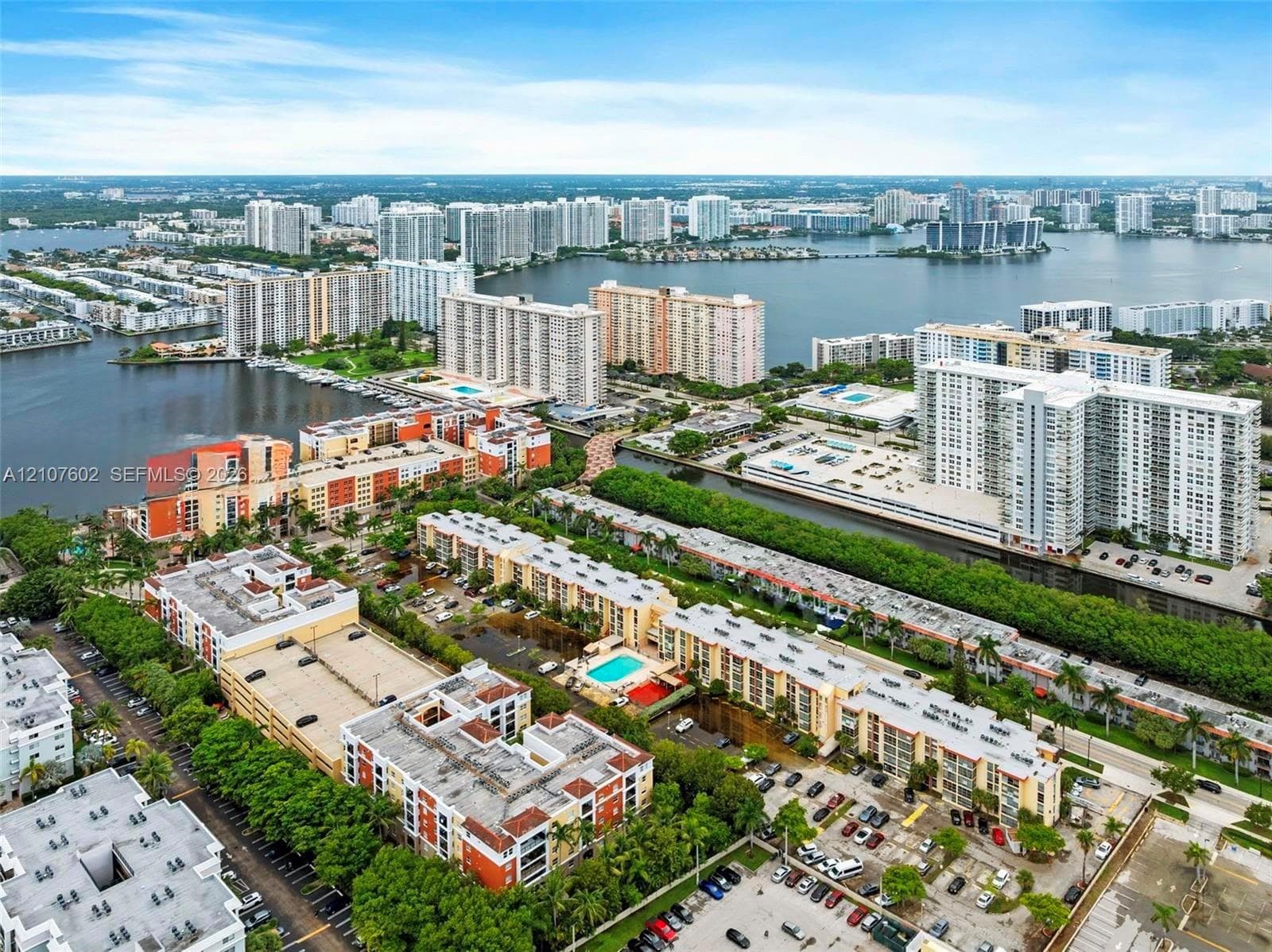 Aerial perspective of waterfront urban landscape featuring canals, residential mid-rise structures, landscaped grounds, and parking facilities