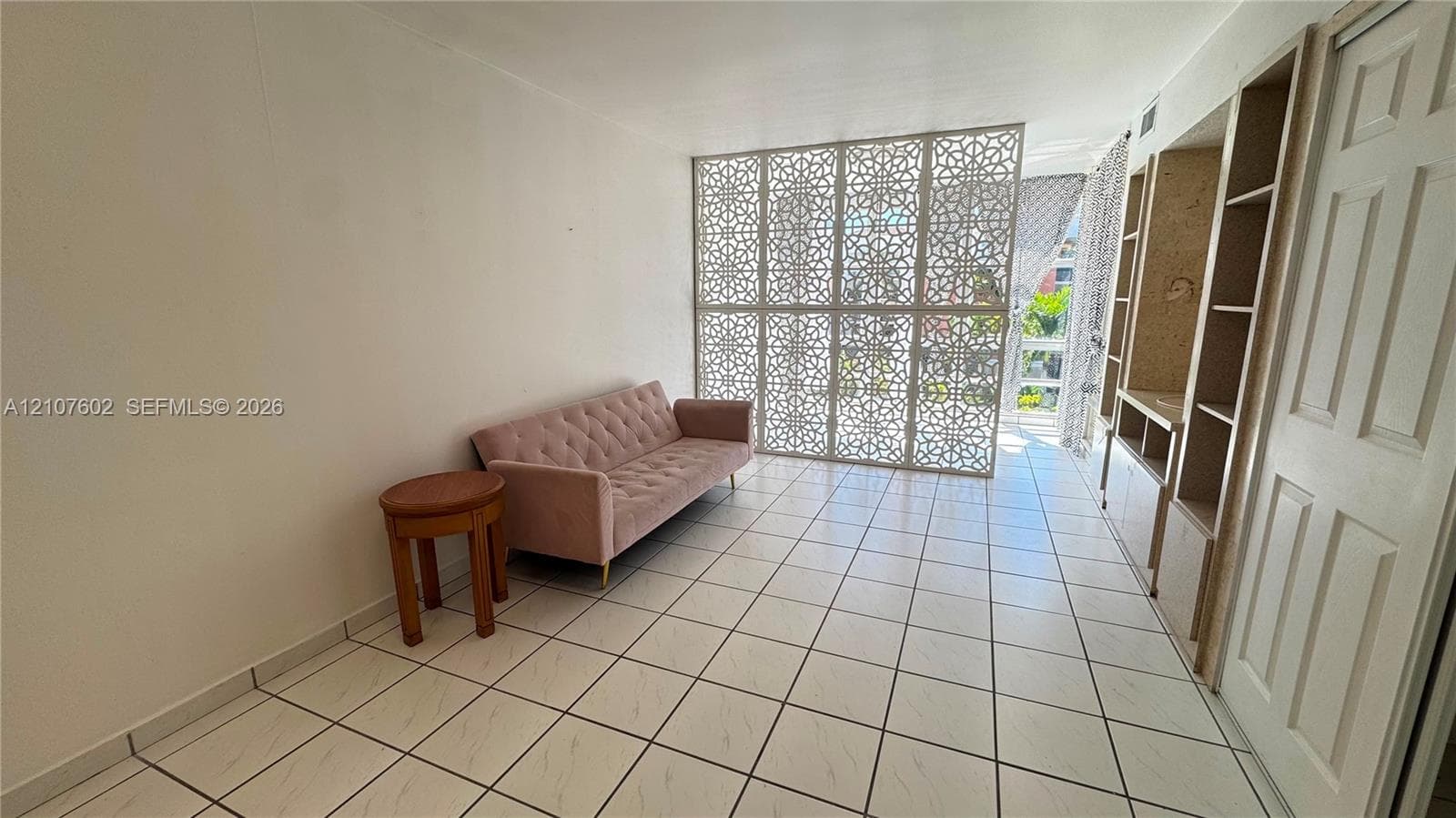Interior space featuring large-format tile flooring, intricate laser-cut privacy screen, and built-in floor-to-ceiling shelving