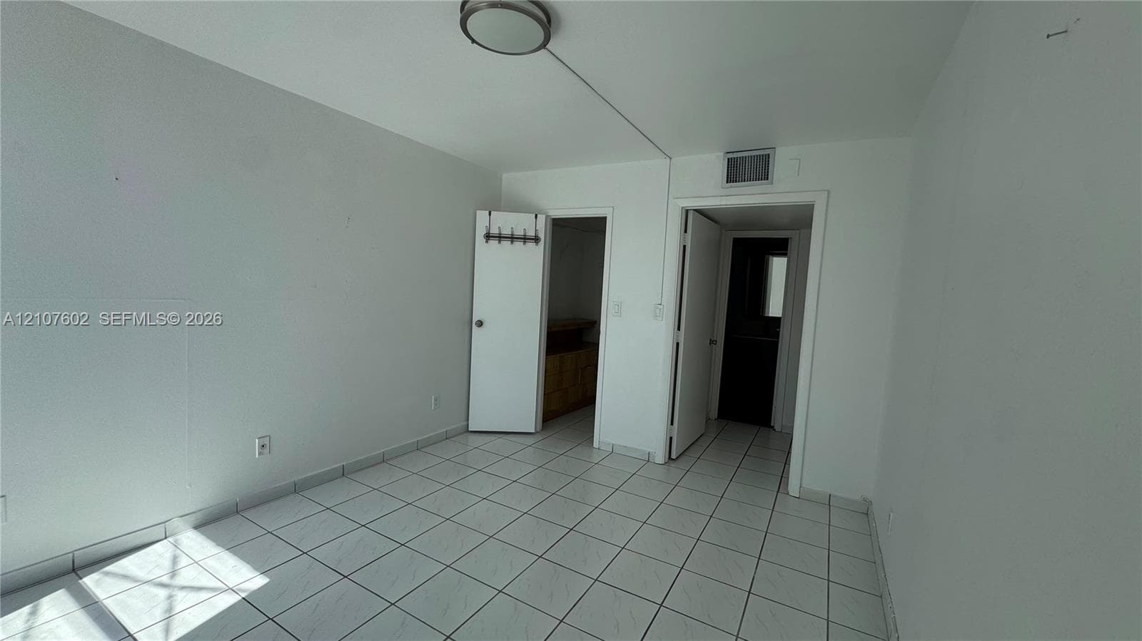 Room featuring white tile flooring, neutral wall paint, and a circular flush-mount ceiling light fixture