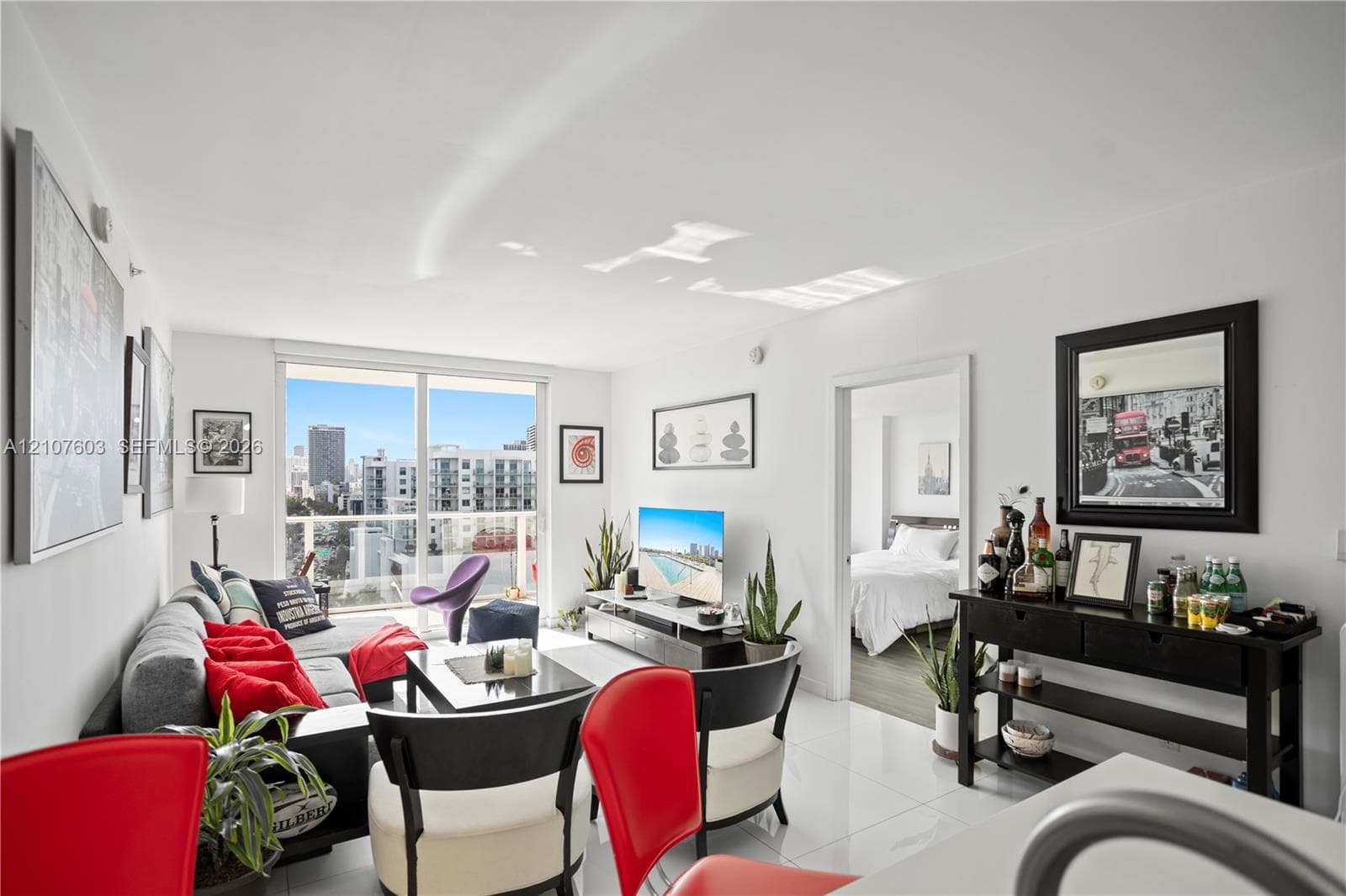 Living area featuring polished tile flooring, floor-to-ceiling glass sliding doors, and a private balcony