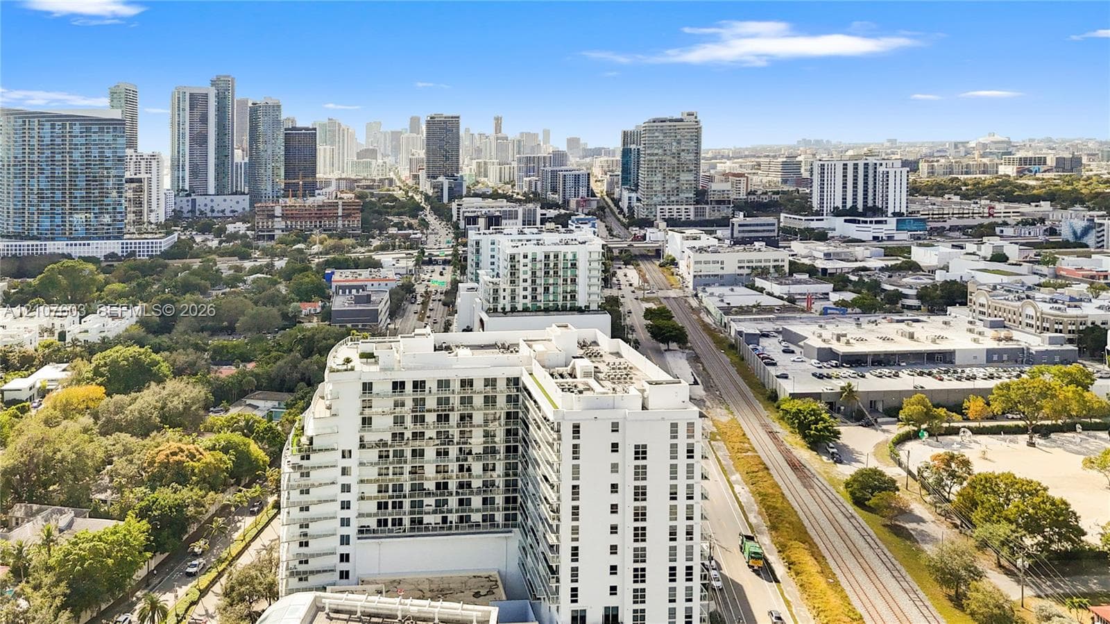 Aerial perspective featuring a multi-story high-rise building with integrated balconies, situated in a metropolitan landscape
