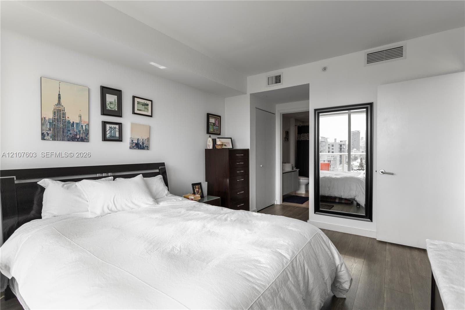 Wood-finish flooring, full-length wall mirror with a black frame, and ceiling-integrated climate control system