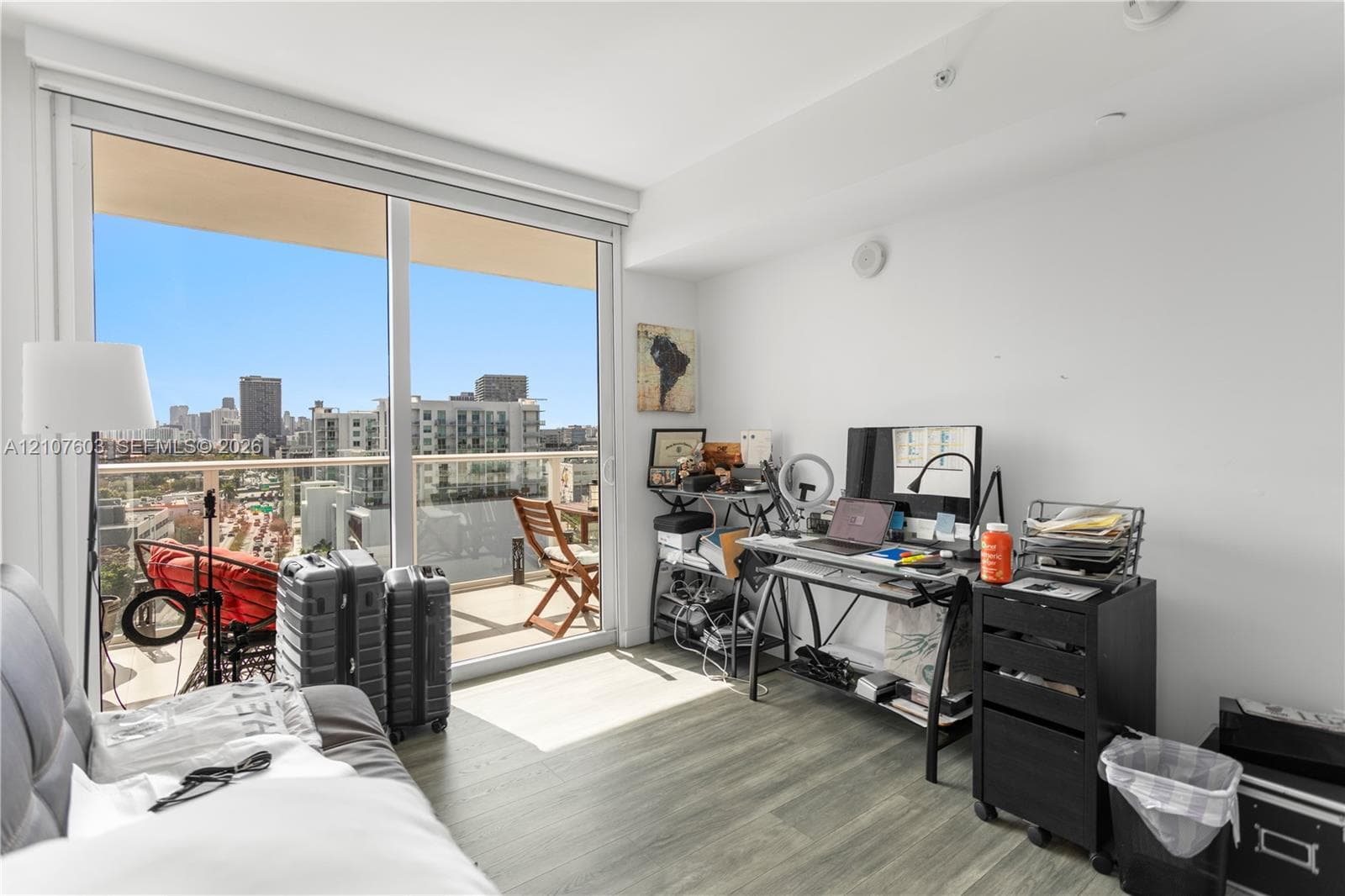Floor-to-ceiling sliding glass door, private balcony, wood-finish flooring, and expansive urban scenery