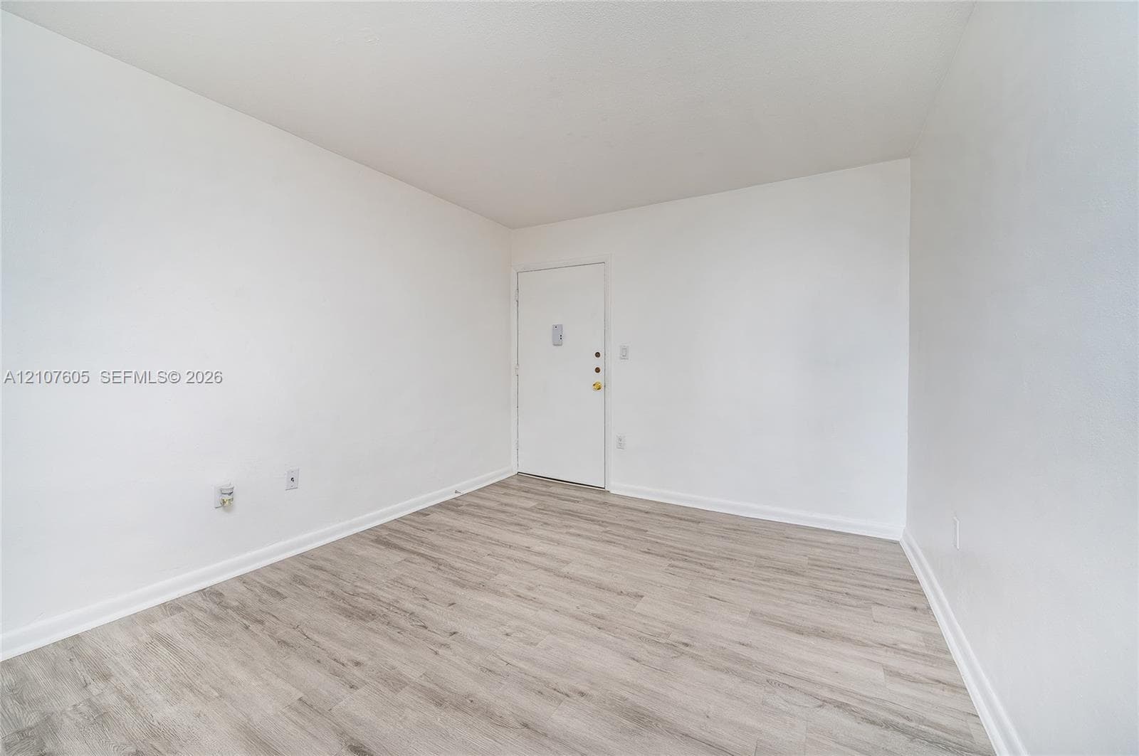 Neutral interior featuring wood-finish flooring and stark white walls