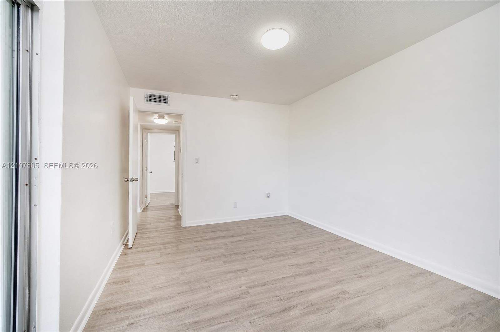 Room featuring light-toned wood-finish flooring, neutral walls, and a circular flush-mount ceiling light fixture