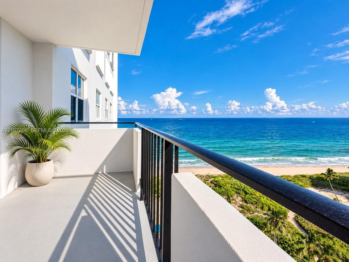 Covered balcony featuring concrete flooring, black metal railing, and ocean horizon backdrop