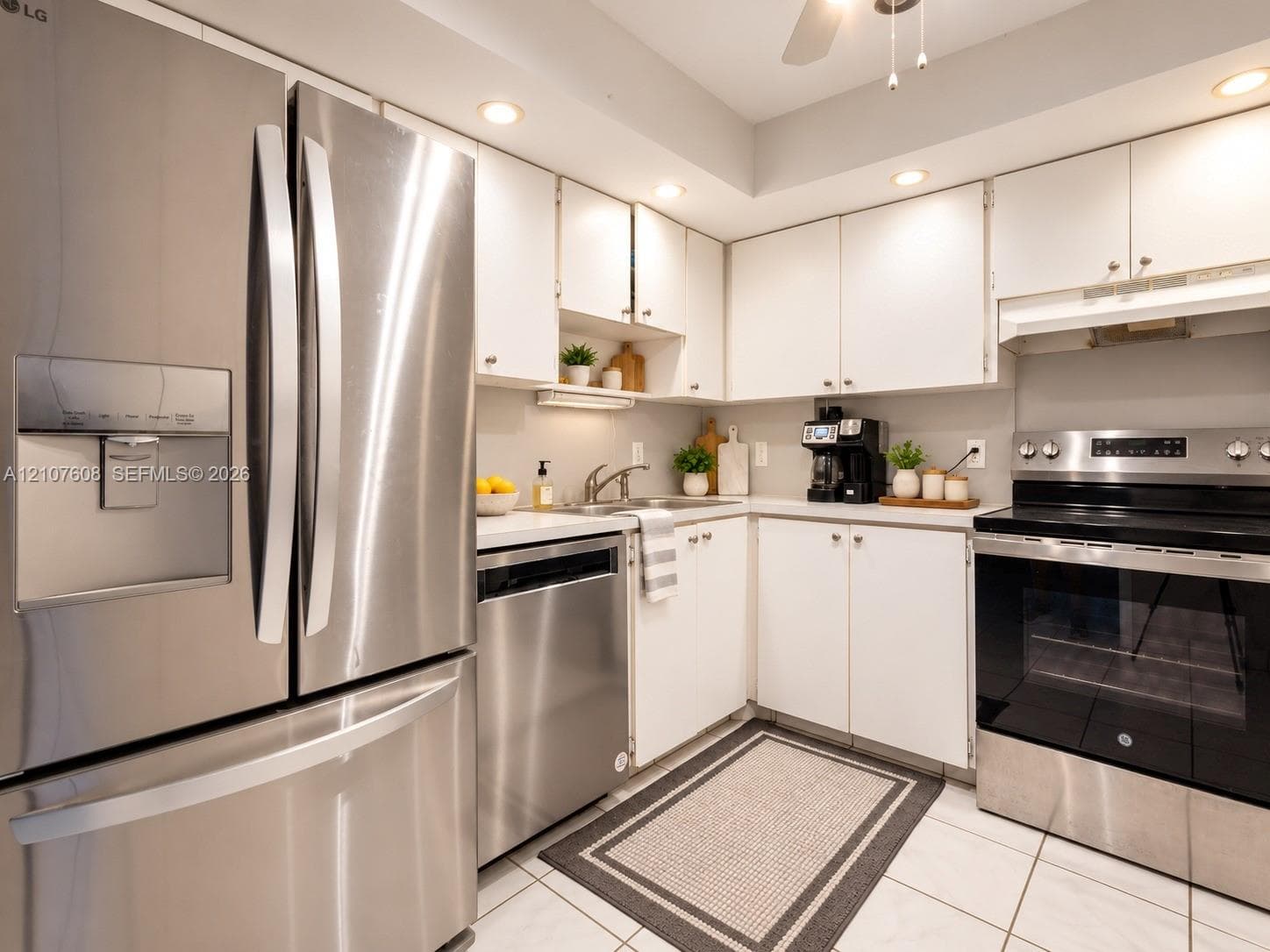 Kitchen featuring white cabinetry, stainless steel appliances, recessed ceiling lighting, solid-surface countertops, and tile flooring