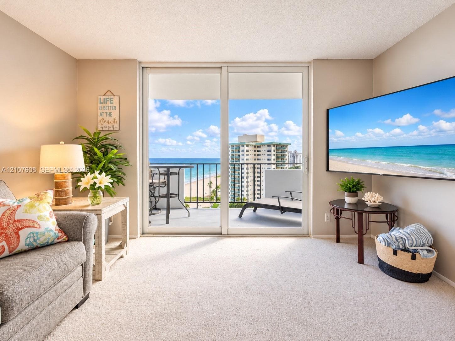 Sliding glass doors opening to a private balcony featuring a metal railing and oceanfront scenery