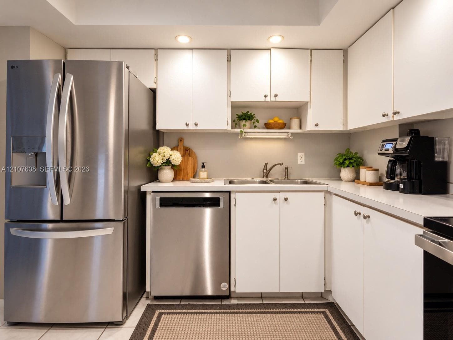 Kitchen featuring white cabinetry, stainless steel French door refrigerator, stainless steel dishwasher, solid-surface countertops, and recessed lighting