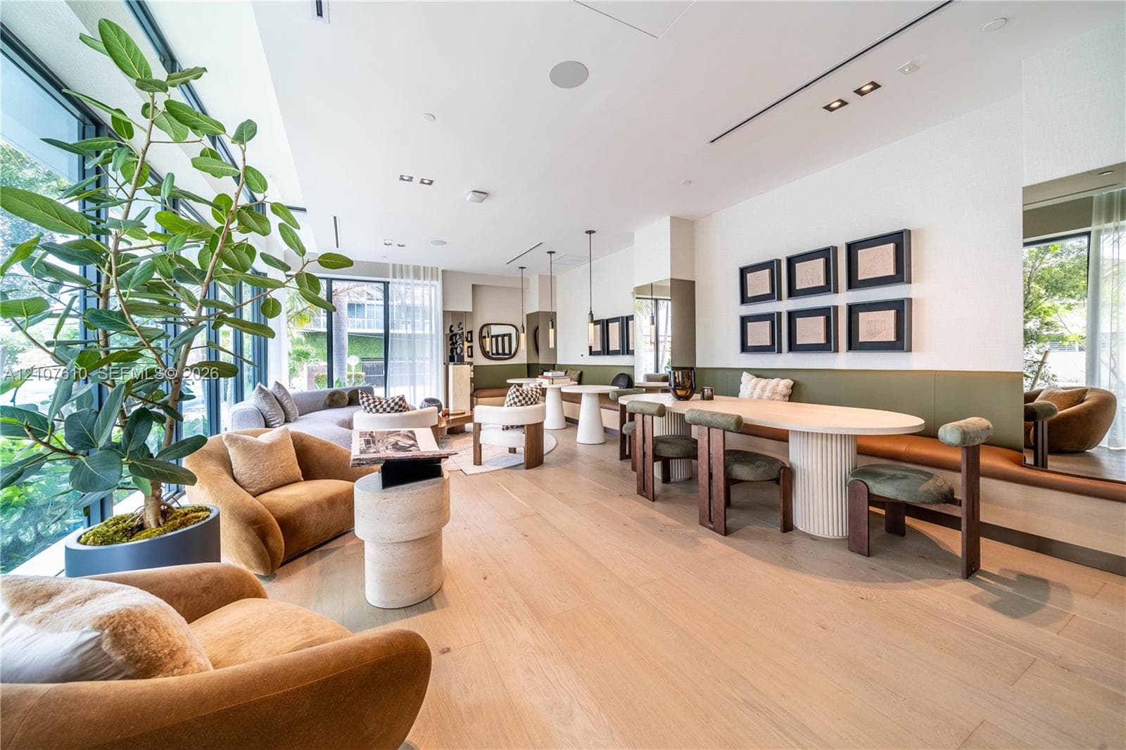 Floor-to-ceiling windows, wide-plank wood-finish flooring, integrated wall-mounted banquette seating, recessed ceiling lighting, and fluted column dining table base