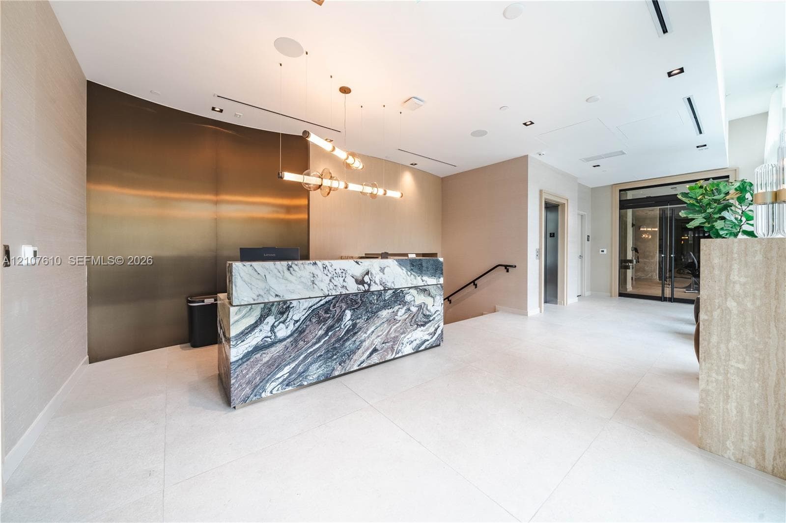 Reception area featuring a stone-fronted desk, metallic wall paneling, tile flooring, and custom tiered pendant lighting