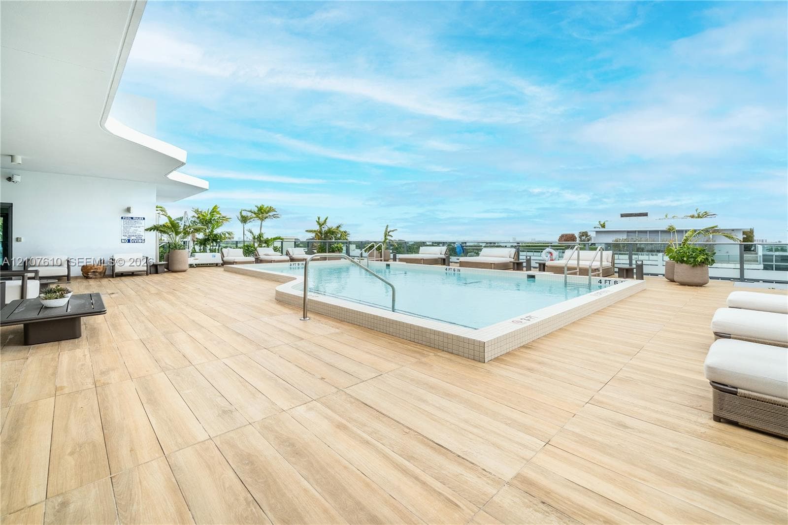 Rooftop terrace featuring a tiled pool, wood-finish flooring, metal perimeter railings, and integrated lighting