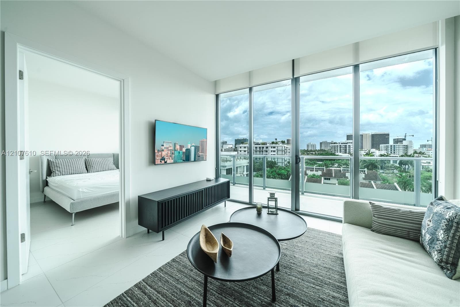 Floor-to-ceiling windows, glass-panel balcony railing, tile flooring, and urban scenery