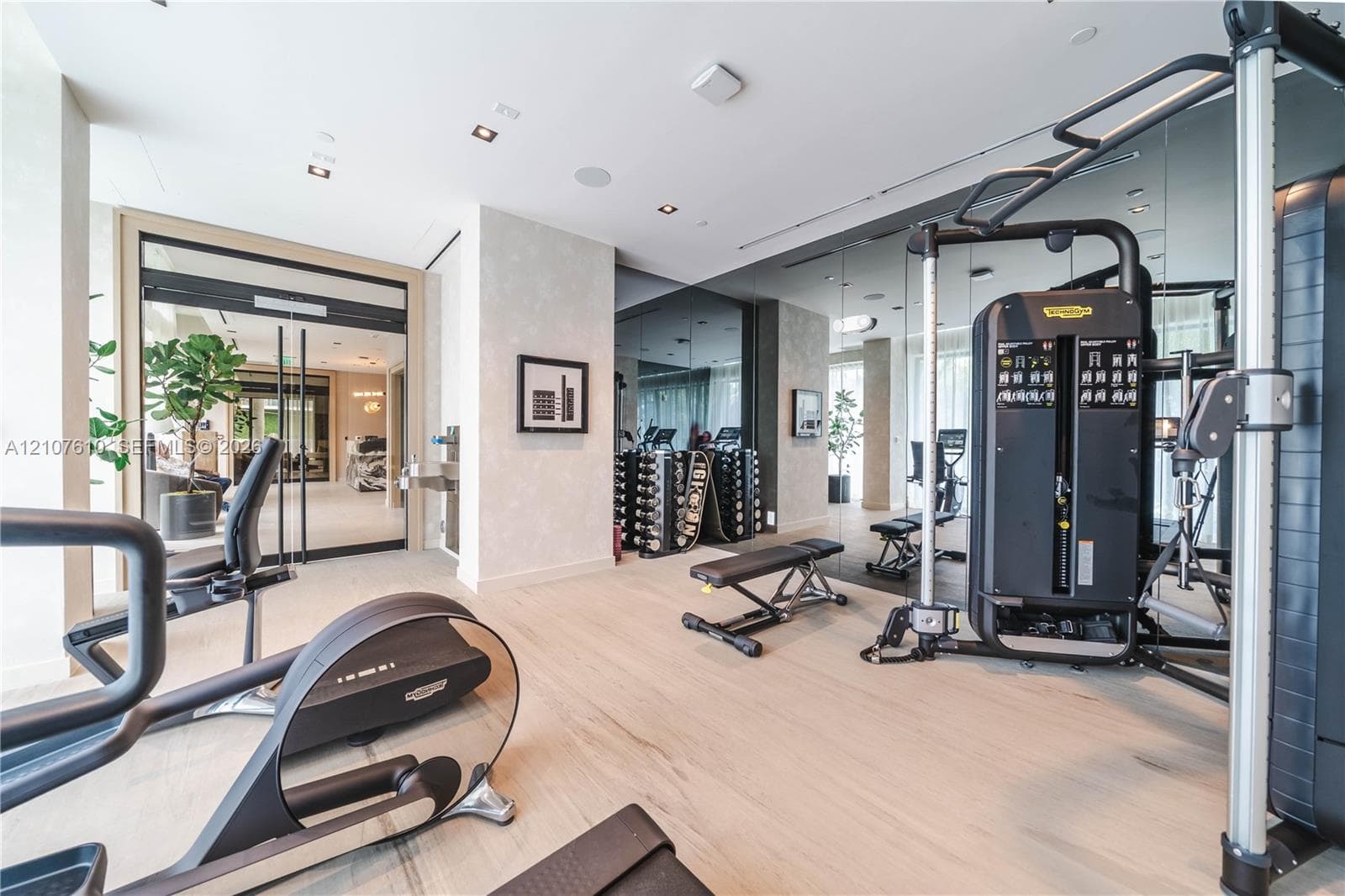Fitness center featuring wood-finish flooring, floor-to-ceiling mirrored walls, recessed lighting, and wall-mounted water fountain
