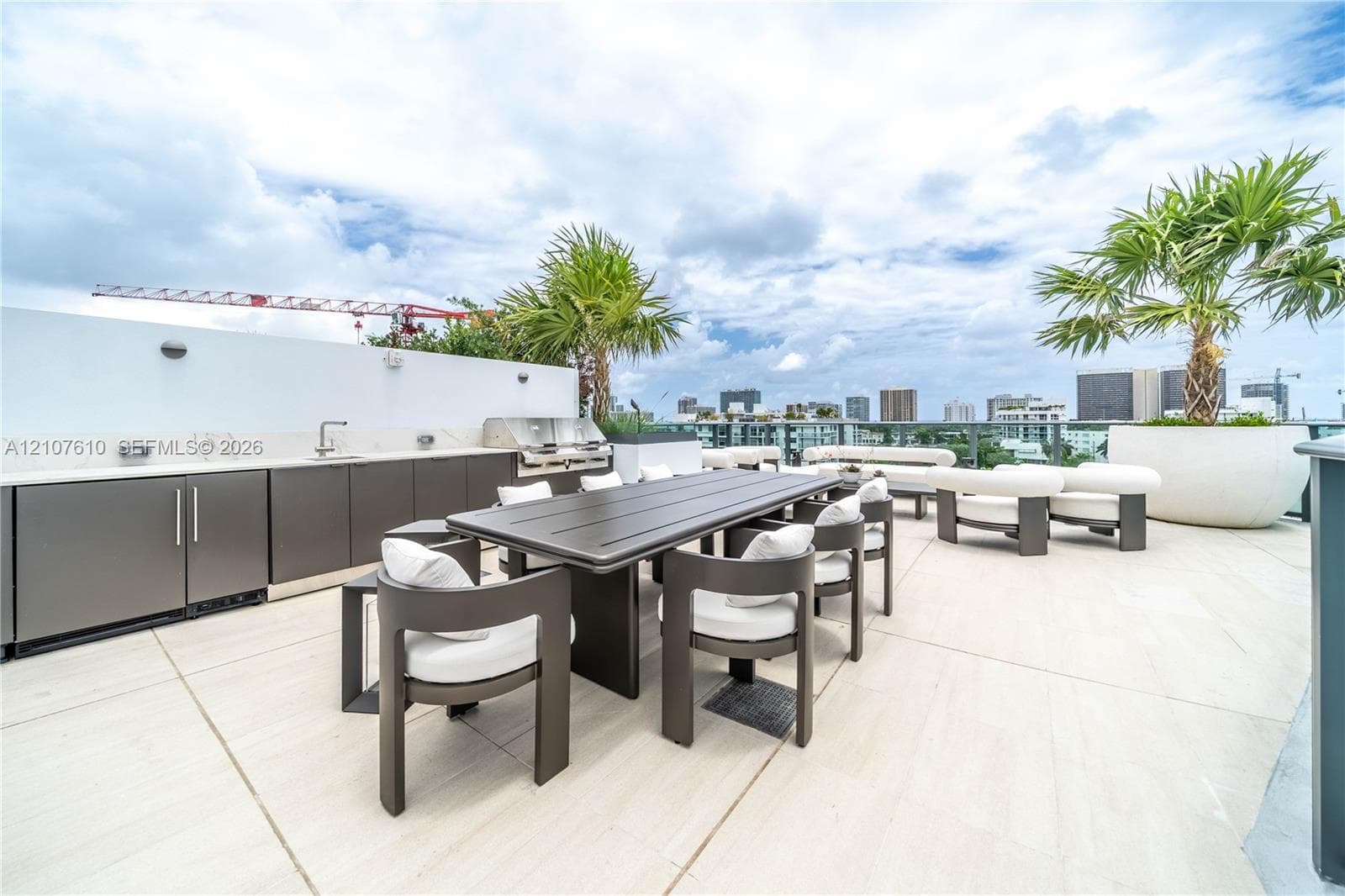Rooftop terrace featuring large-format tile flooring, outdoor kitchenette with stone countertop and stainless steel built-in grill, glass panel railing, and integrated planters