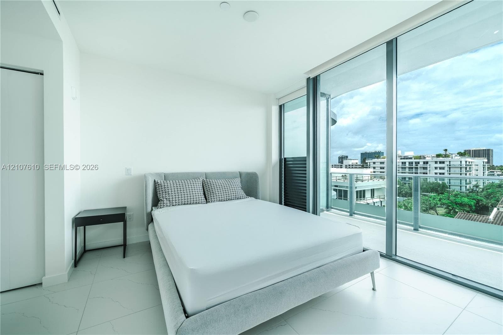 Floor-to-ceiling glass sliding doors, private balcony with metal railing, and large-format tile flooring