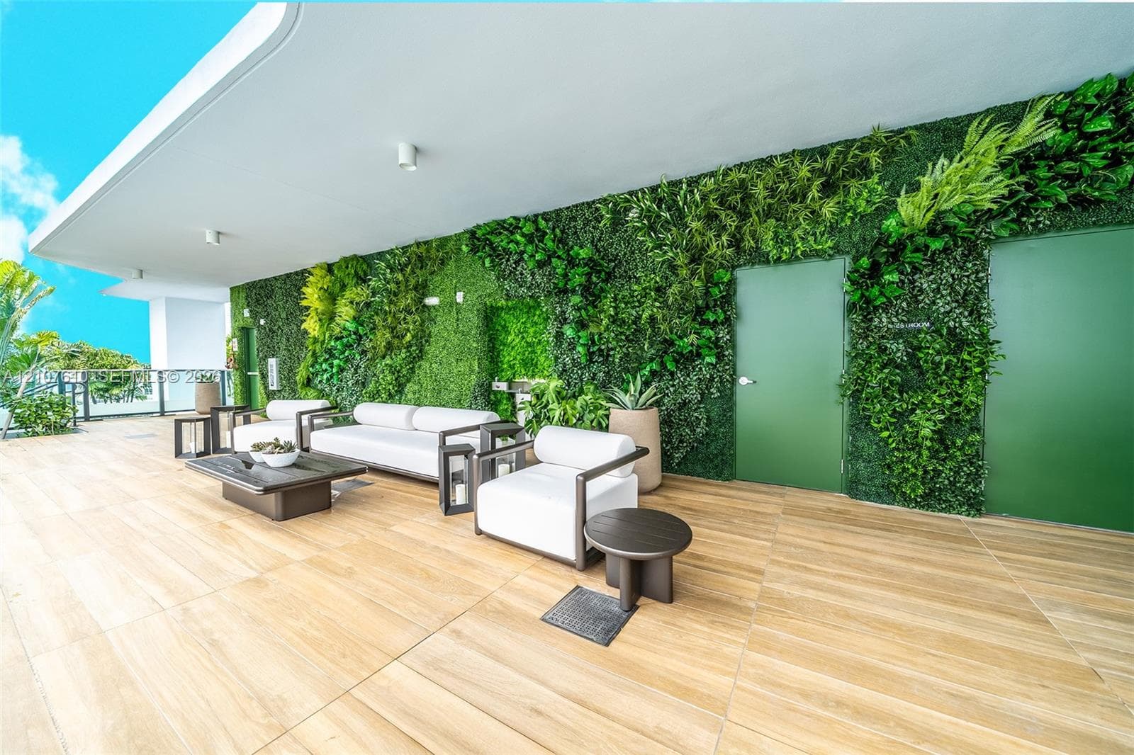 Covered outdoor terrace featuring wood-finish tile flooring, a living plant wall, and integrated ceiling lighting