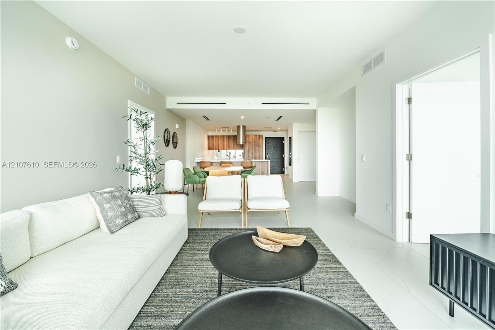 Open-concept interior featuring light-toned flooring, high-contrast cabinetry, recessed lighting, and a cylindrical stainless-steel range hood