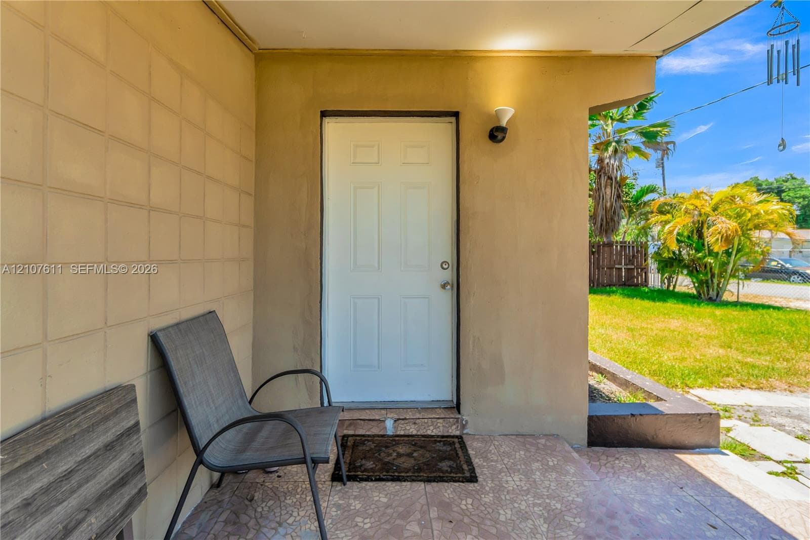 Covered entryway featuring textured concrete block wall, decorative tiled flooring, and exterior wall-mounted light fixture