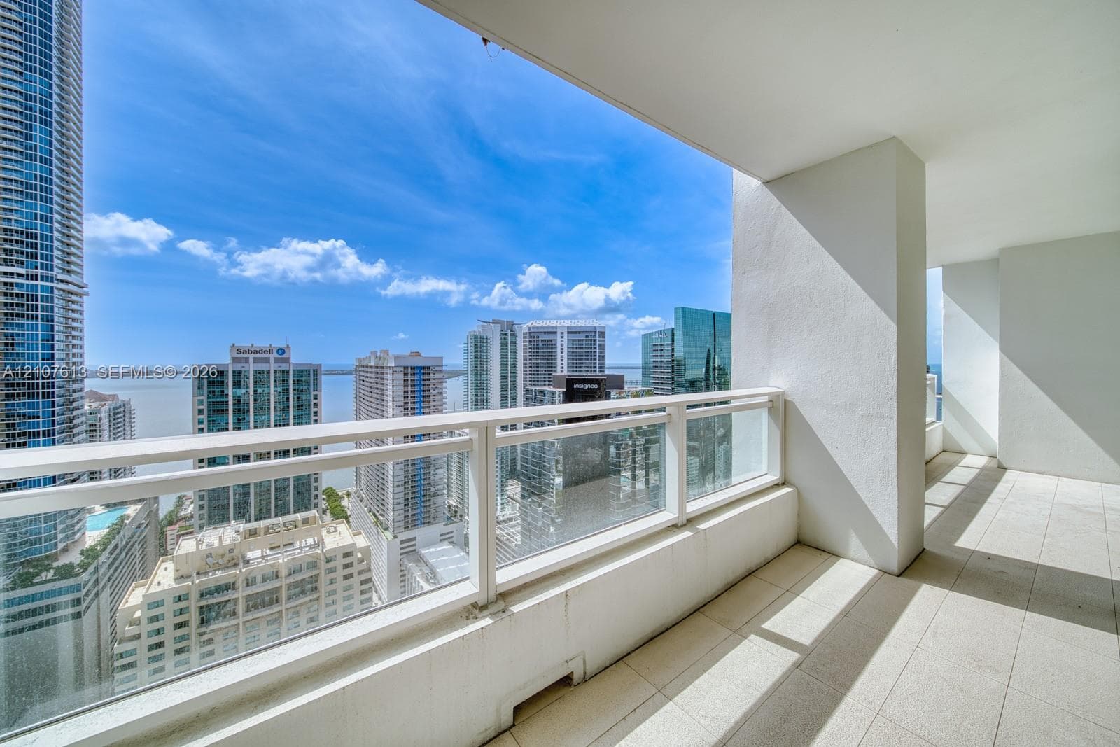 Covered balcony featuring tile flooring and a glass-paneled metal railing