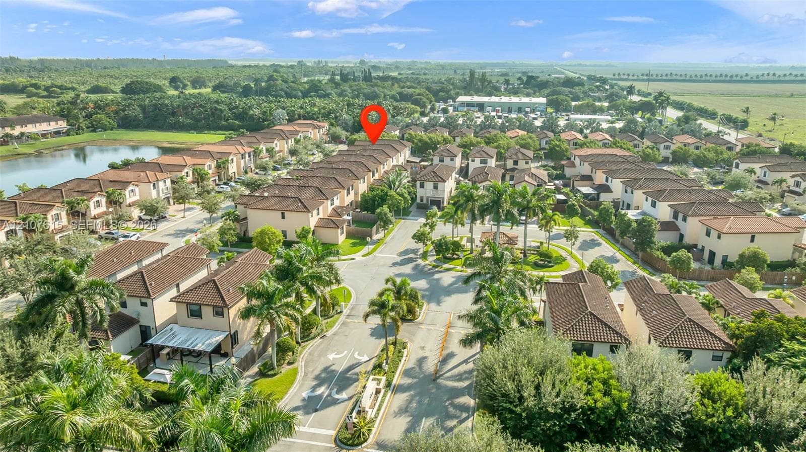 Aerial perspective of residential community featuring multi-level dwellings with tile roofing, paved streets, and landscaped grounds